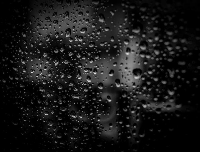 Raindrops on dark glass.