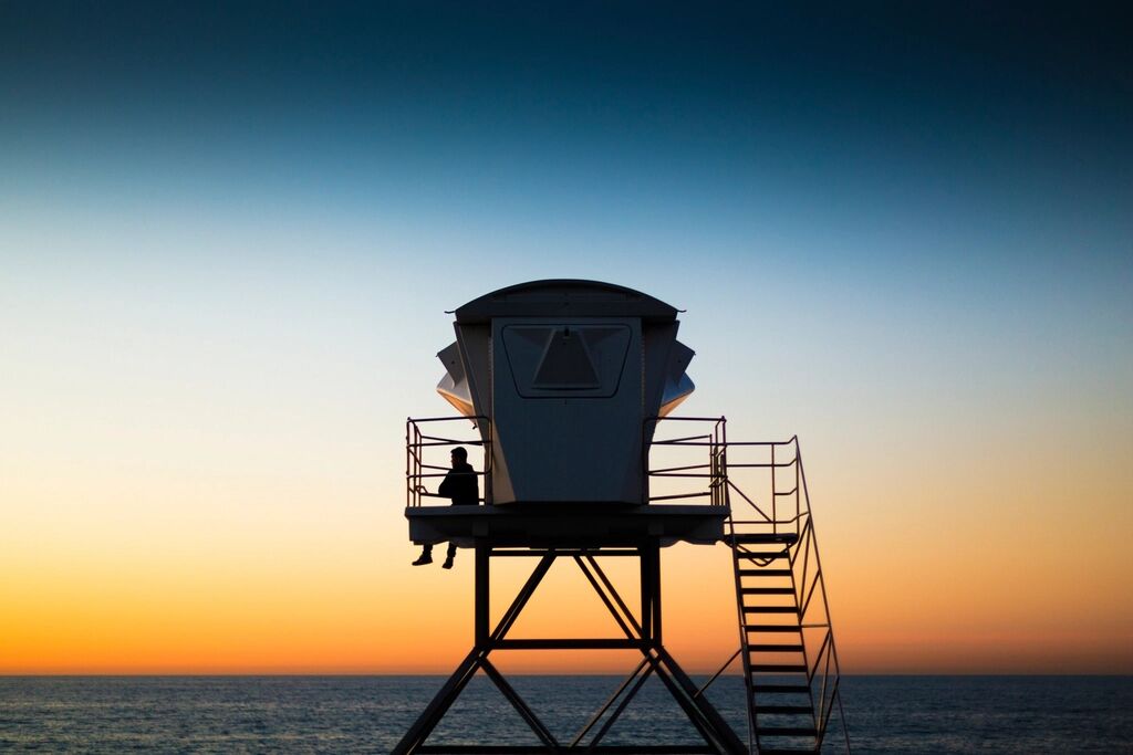 A lifeguard tower silhouetted against the sky at dusk.