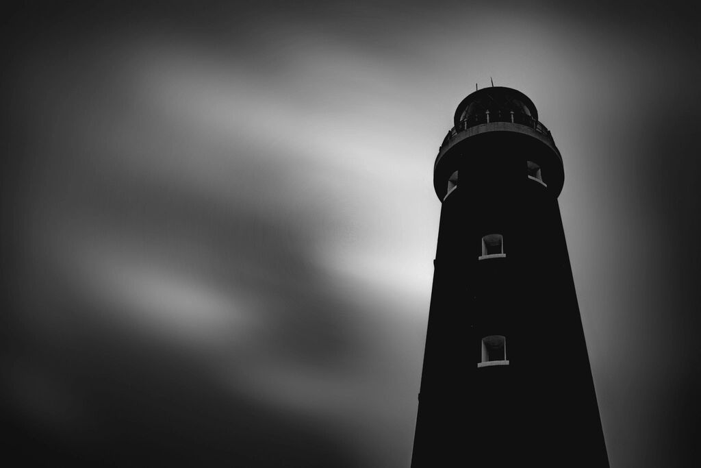 A lighthouse silhouetted against a dark sky.