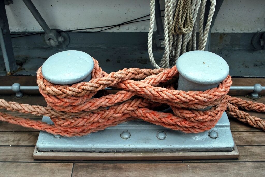 Orange mooring rope tied around a post on a dock.