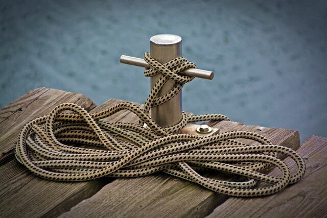 A rope wound around a post on a wooden pier.