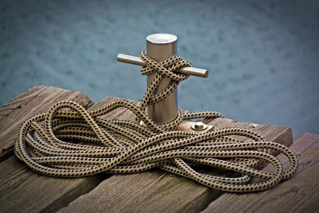 A rope wound around a post on a wooden pier.